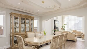 A dining area with a large wooden table and matching chairs, a glass-fronted china cabinet, and a comfortable seating area with sofas.
