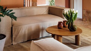 Una sala de estar acogedora con un sofá, una mesa redonda de madera y una planta en maceta.