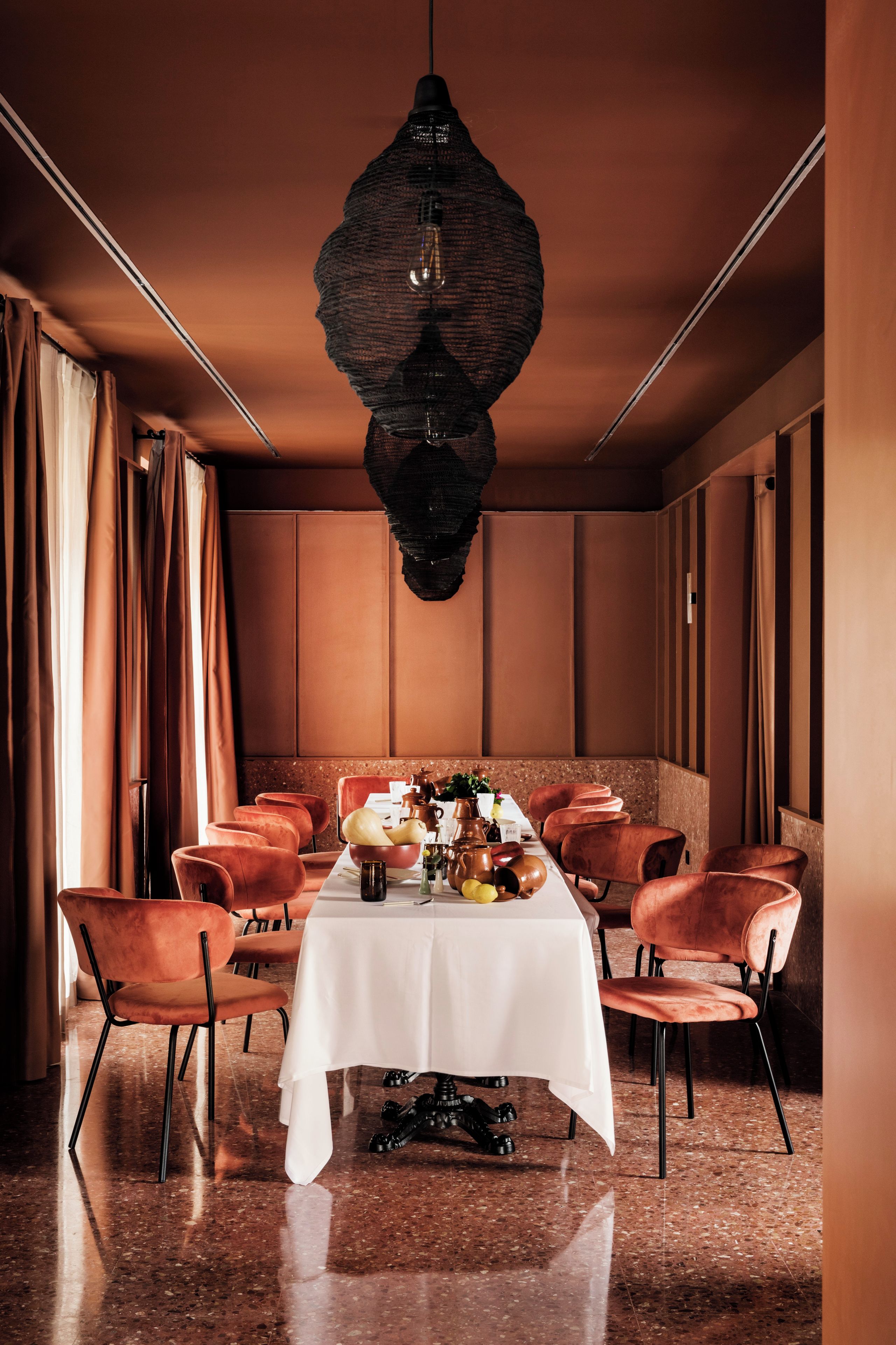 Un comedor con una mesa larga, varias sillas y una lámpara colgante decorativa.