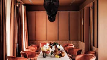 Un comedor con una mesa larga, varias sillas y una lámpara colgante decorativa.