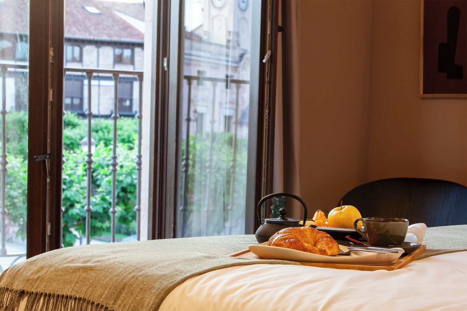 Ein Hotelzimmer mit einem Bett, einem Tablett mit Croissants, einem Teekessel und einer Tasse.