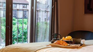Ein Hotelzimmer mit einem Bett, einem Tablett mit Croissants, einem Teekessel und einer Tasse.