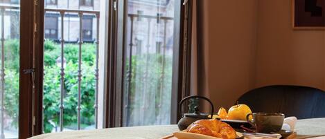 Une chambre d’hôtel avec un lit, un plateau avec des croissants, une théière et une tasse.