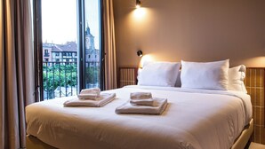 Habitación de hotel con una cama grande, dos almohadas, una mesita de noche y una ventana con cortinas.