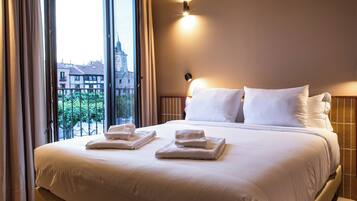 Habitación de hotel con una cama grande, dos almohadas, una mesita de noche y una ventana con cortinas.