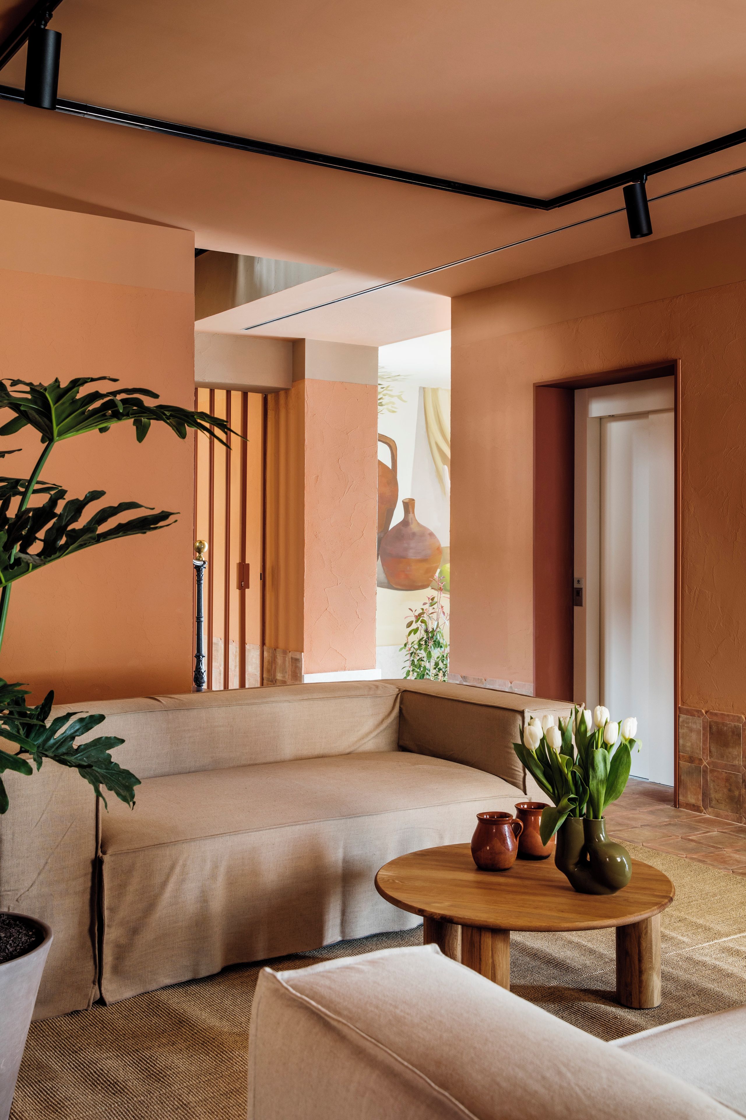 Una sala de estar acogedora con un sofá, una mesa redonda de madera y una planta en maceta.