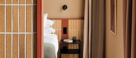 A hotel room with a bed, bedside table, and a view of the hallway.