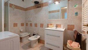 Un baño con inodoro, bidé, lavamanos y un espejo sobre el lavamanos.