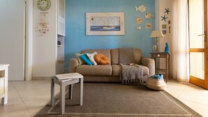 Una sala de estar con pared azul, un sofá, una mesita y una lámpara.