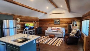 A log cabin interior with a kitchenette, a sofa, and a television. - Cookie's Cabin is a charming little cabin in adventurous Kemmerer! (Kemmerer)