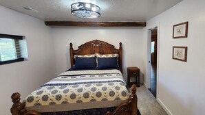 A bedroom with a wooden bed, a nightstand, and a ceiling light fixture. - Cookie's Cabin is a charming little cabin in adventurous Kemmerer! (Kemmerer)