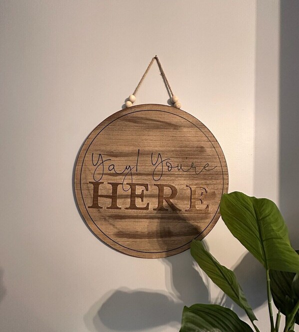 A wooden sign with the text "You're Here" hanging on a wall.