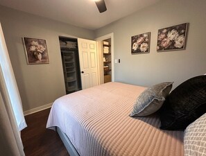 A bedroom with a bed, a closet, and three floral paintings on the wall. - Relax and Roscoe Apartment (Coshocton)
