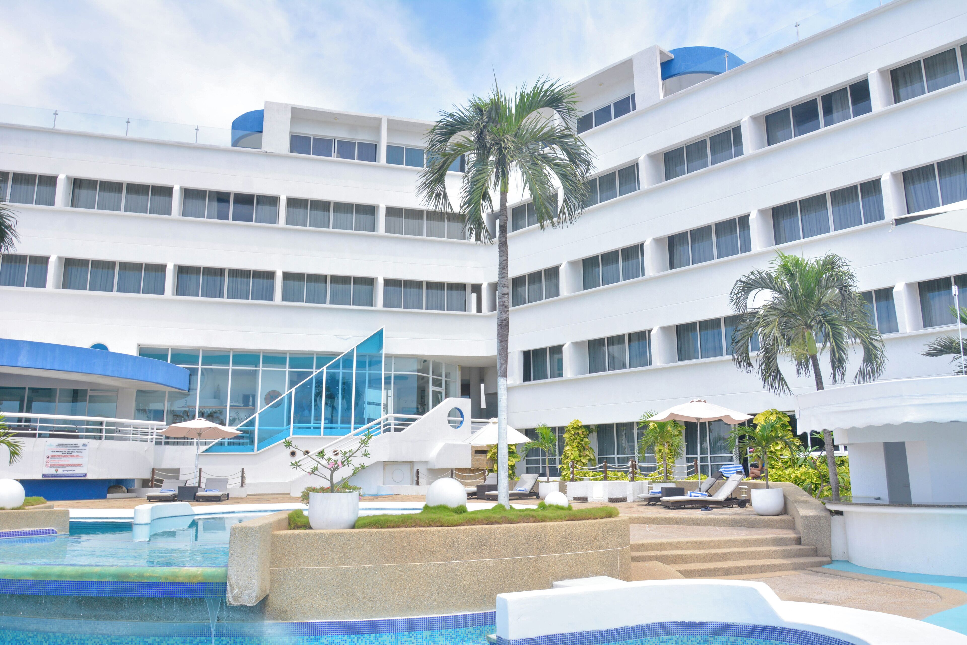 A hotel with a pool area, multiple floors, and outdoor seating.
