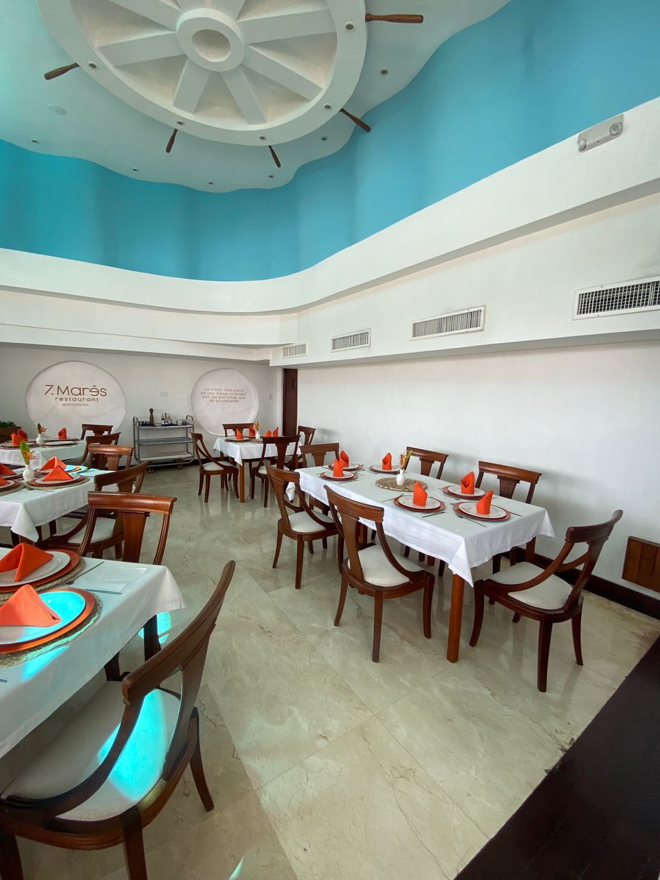 Un ristorante con tavoli rotondi, sedie di legno e un soffitto blu.