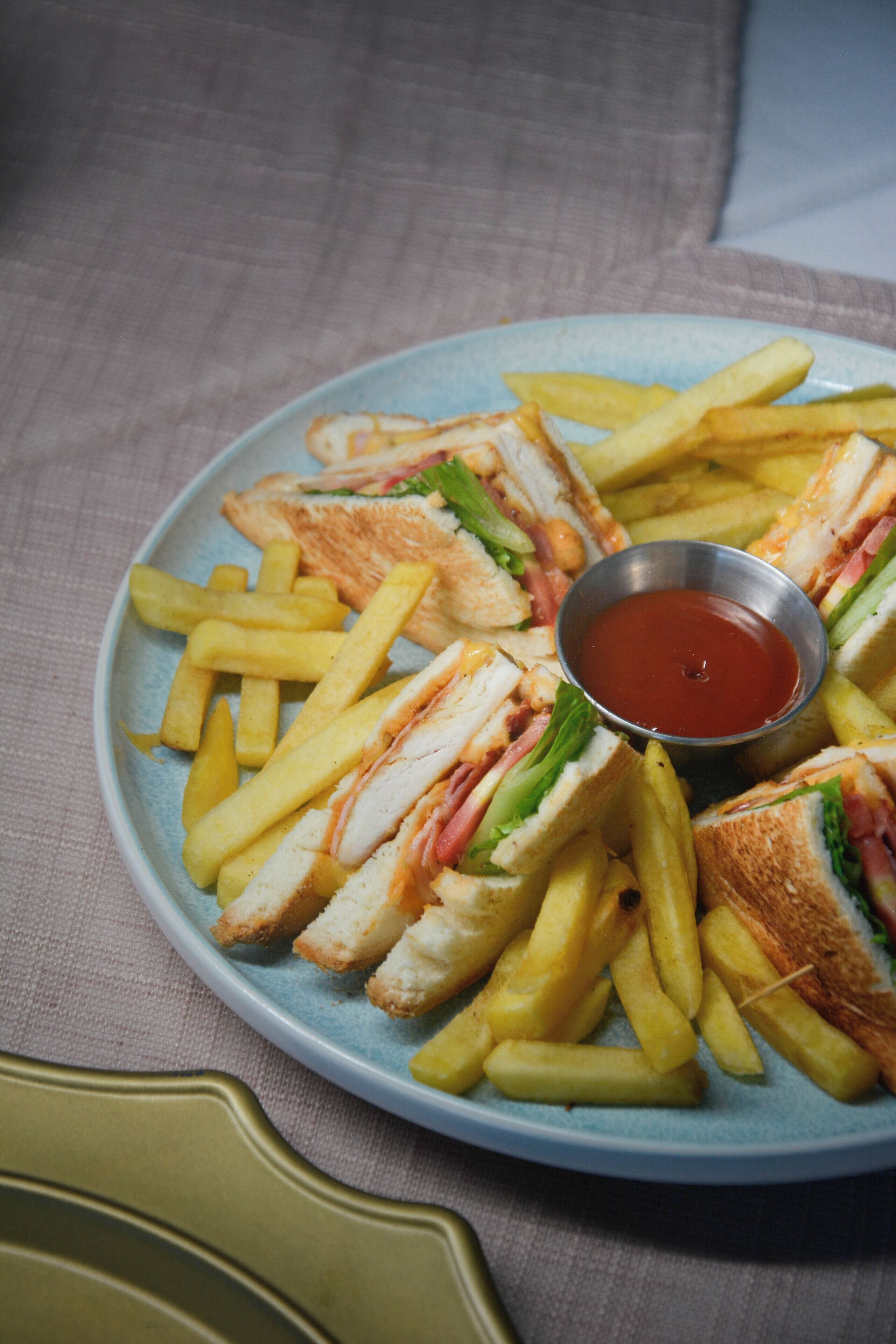 Um prato de sanduíches e batatas fritas com um pequeno recipiente de ketchup.