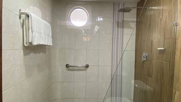 A modern bathroom with a glass shower enclosure, a wooden vanity, and a white toilet.