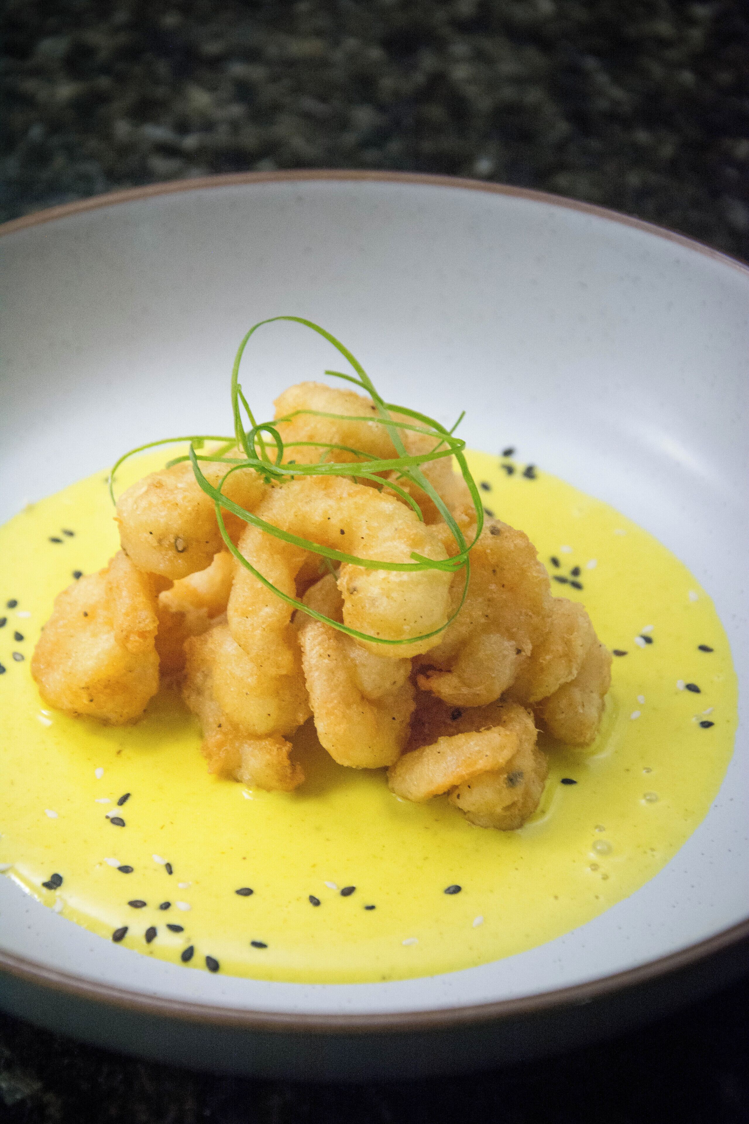 A plate of food with a yellow sauce and green garnish.