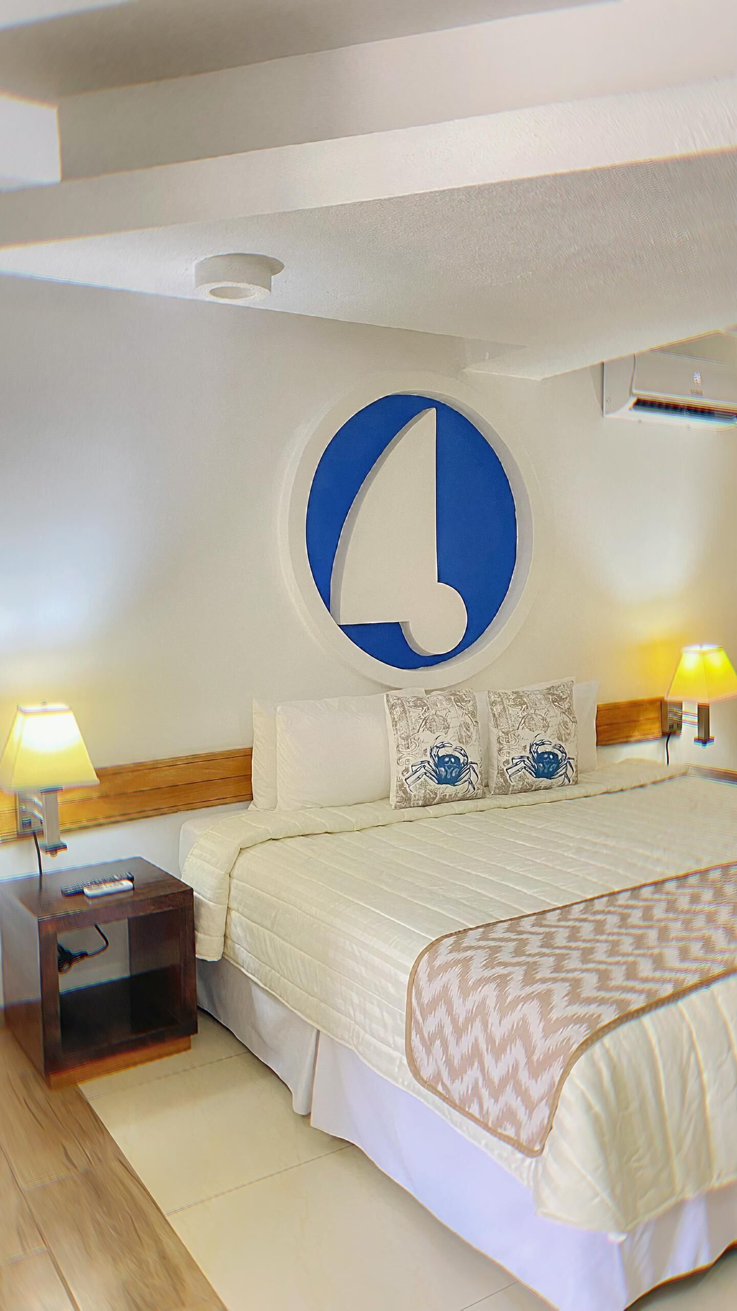 Ein Schlafzimmer mit einem großen Bett, zwei Nachttischlampen, einem Nachttisch und einer runden Wanddekoration.