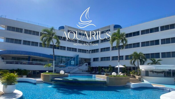 A modern hotel with a central pool, multiple floors, and palm trees.