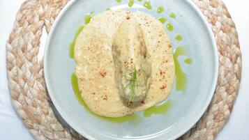 A plate with a creamy dish, possibly a dip or sauce, garnished with herbs and spices, served on a woven mat.