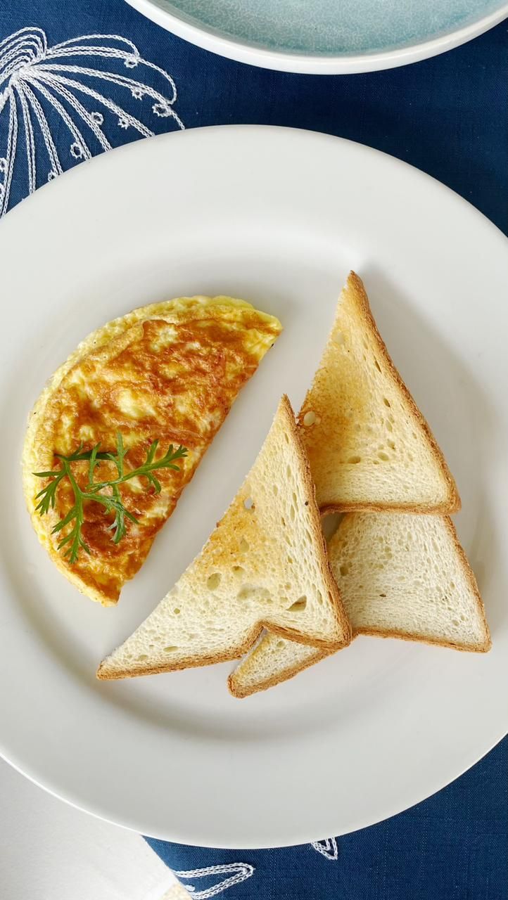 A plate with an omelette and three slices of toast on a white plate.