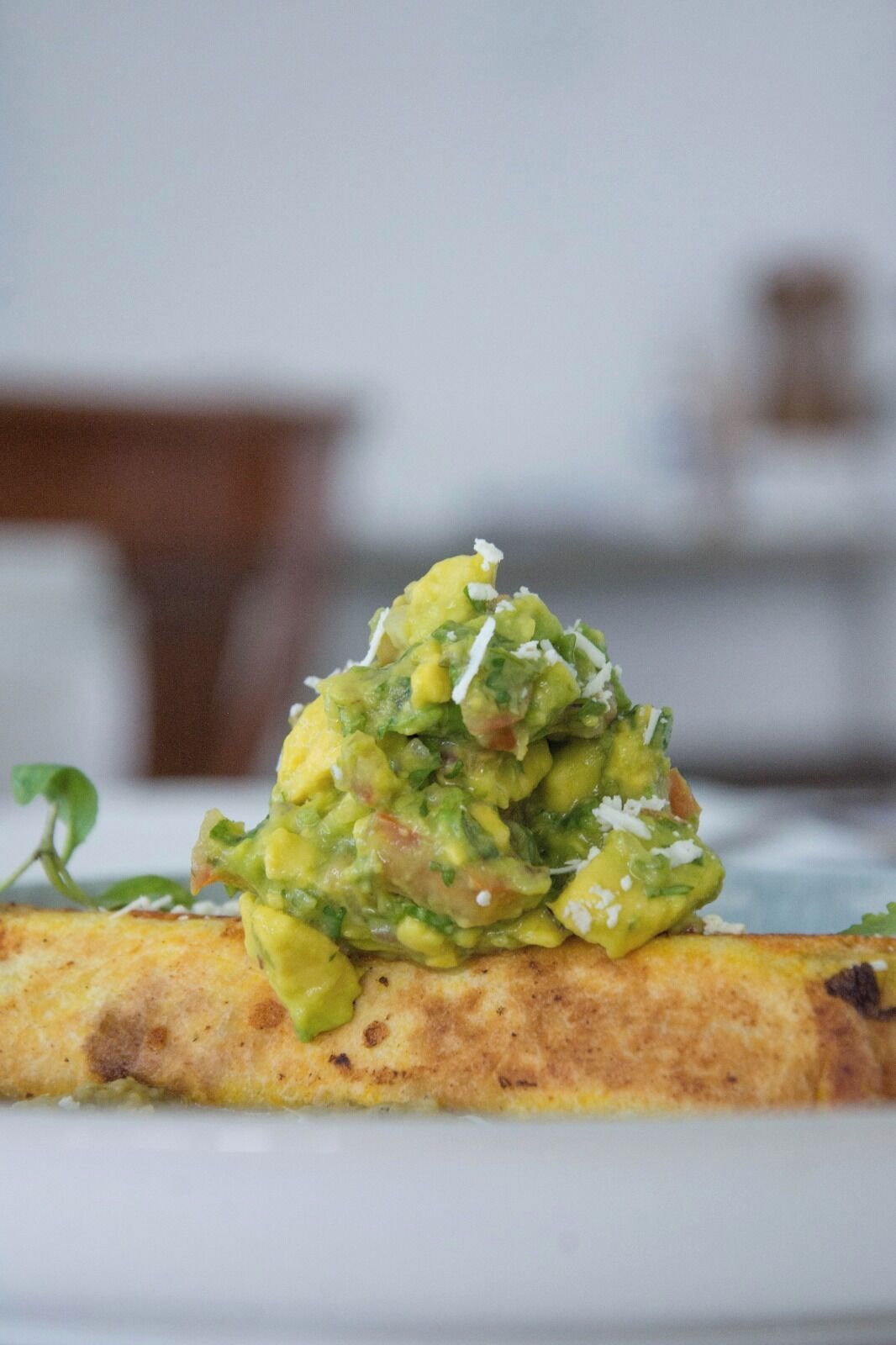 A plate with a food item, possibly a dish with a green topping, on a white plate.