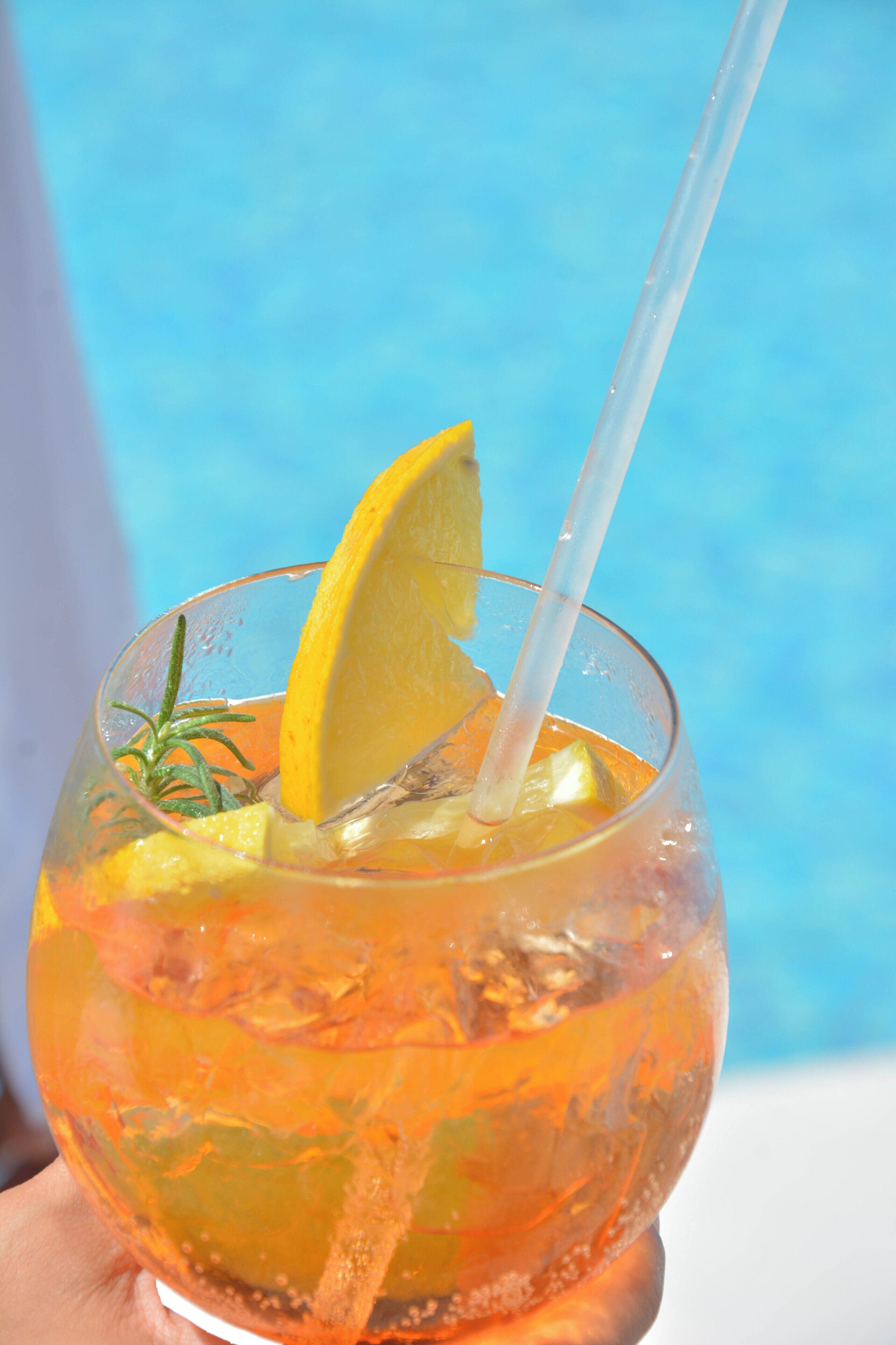 Un verre à cocktail avec une tranche de citron et une paille, présenté sur un fond bleu.