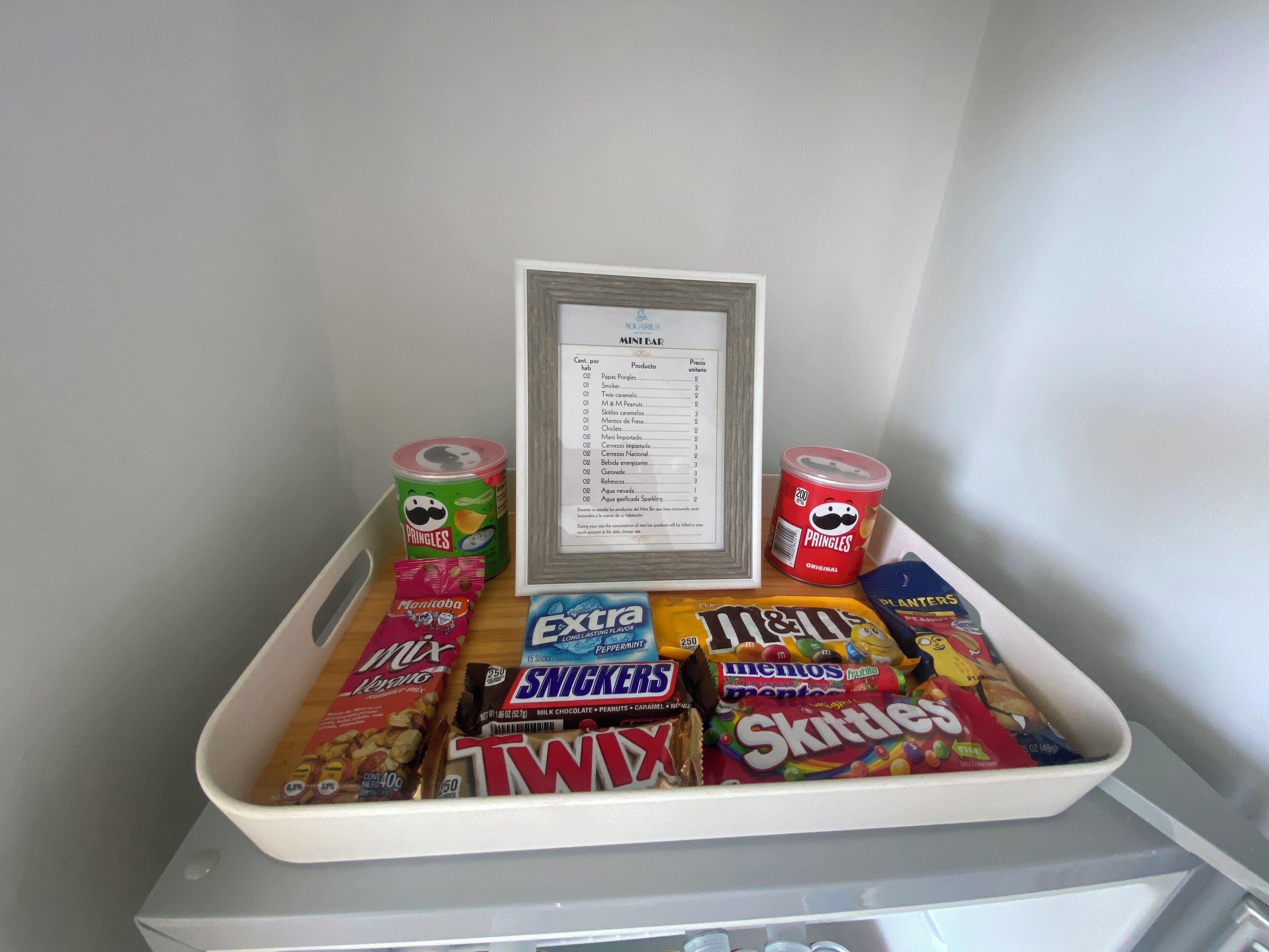 A snack tray with various candies and snacks, including M&M's, Twix, Skittles, and Pringles.