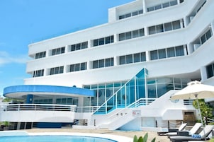 Un hotel moderno con piscina, una zona cubierta y una escalera que conduce a los pisos superiores.