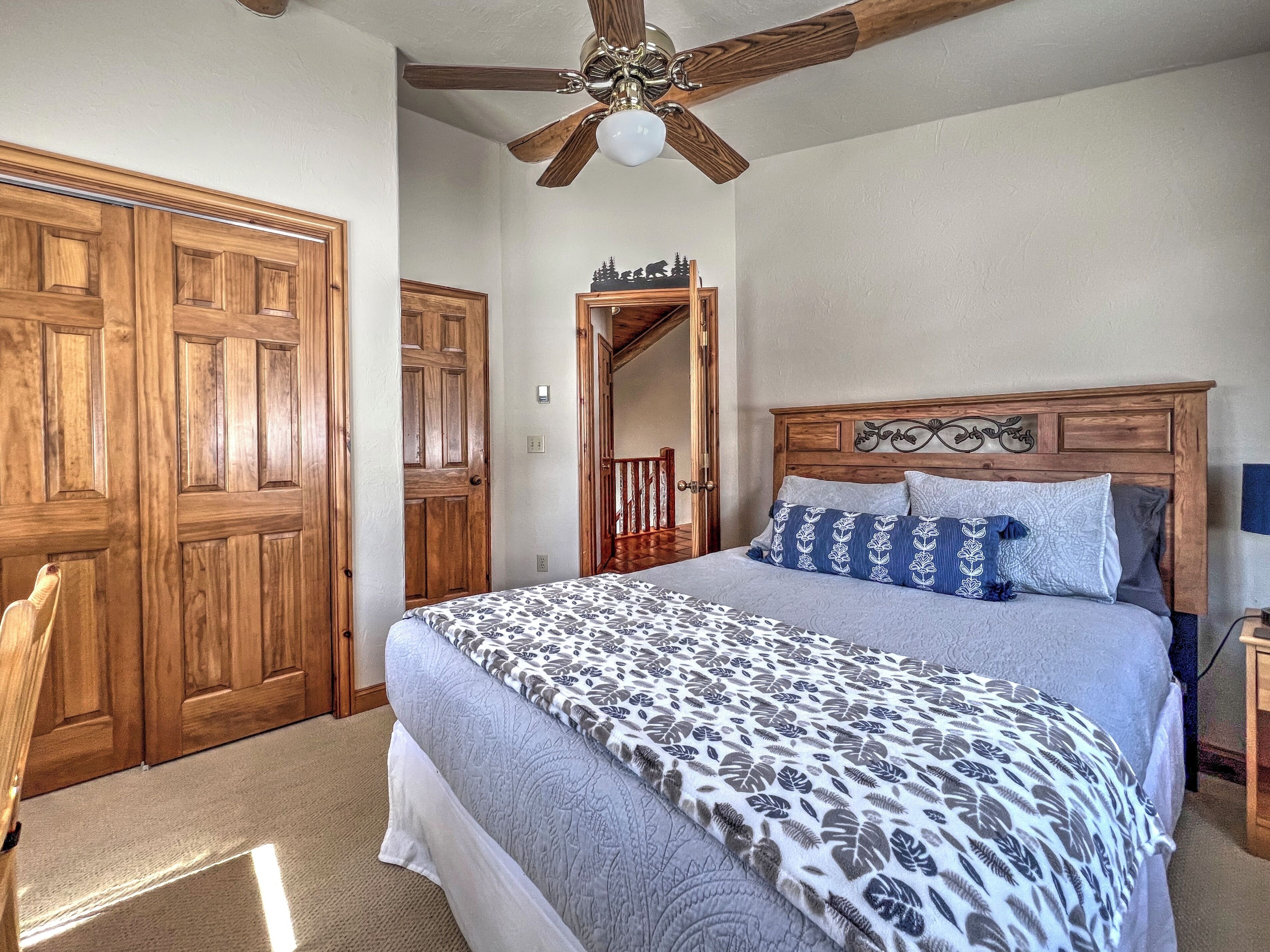 A bedroom with a wooden bed, a ceiling fan, and a large wooden door.
