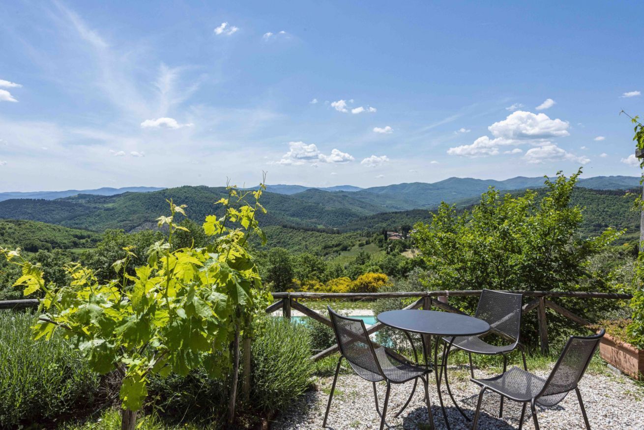 A terrace with a table and chairs overlooking a mountainous landscape.