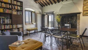 A cozy living room with a fireplace, a bookshelf, a dining table with chairs, and a sofa.