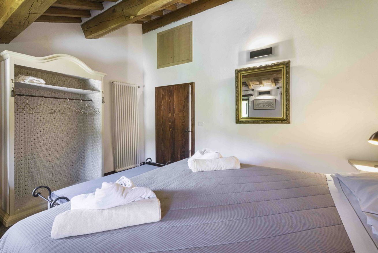 Une chambre d’hôtel avec deux lits, une armoire, un miroir et un radiateur.