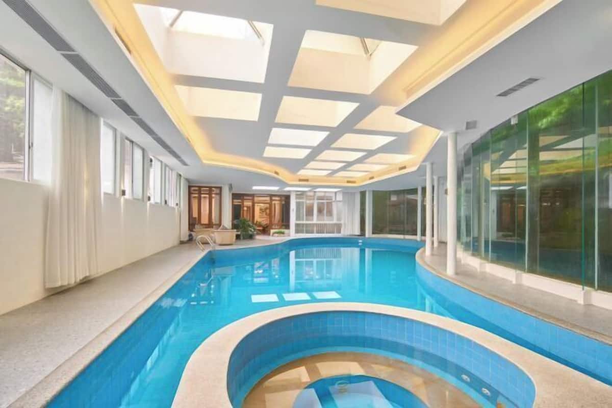 Une piscine intérieure dotée d’un toit ouvrant et de murs en verre.