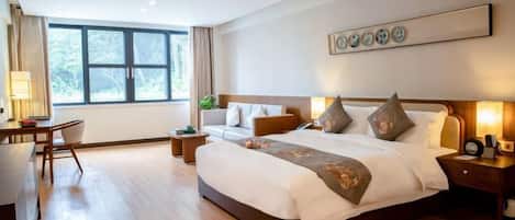 A hotel room with a large bed, bedside tables, a desk, and a window.