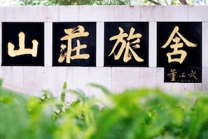 A wall with large black and gold characters, likely a name or title, and a smaller inscription below. - Guangzhou Mountain Villa (Guangzhou)