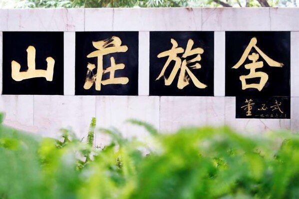A wall with large black and gold characters, likely a name or title, and a smaller inscription below. - Guangzhou Mountain Villa (Guangzhou)