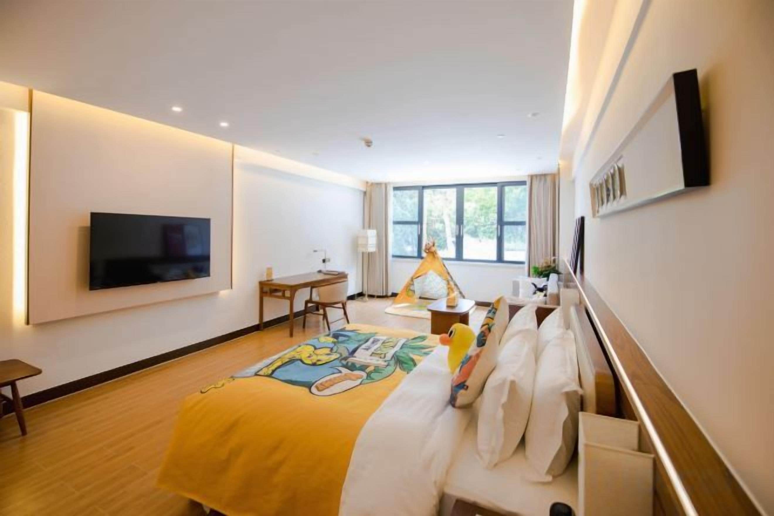 A hotel room with a bed, a desk, a chair, a TV, and a window.
