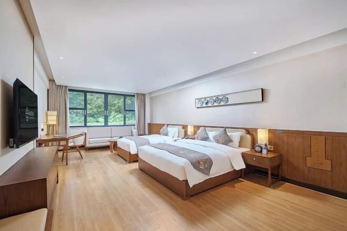 Une chambre d’hôtel avec deux lits, un bureau, une télévision et une grande fenêtre.
