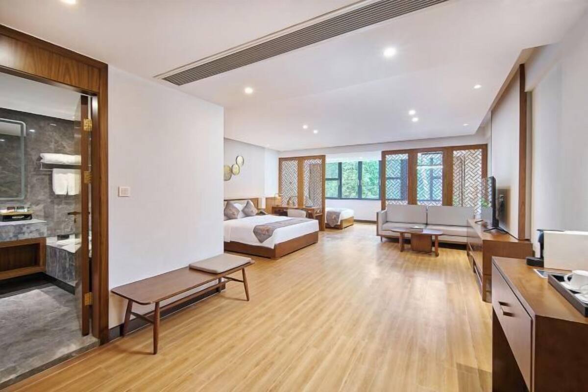Une chambre d’hôtel moderne avec un plancher en bois, un lit, un canapé, un bureau et une télévision.