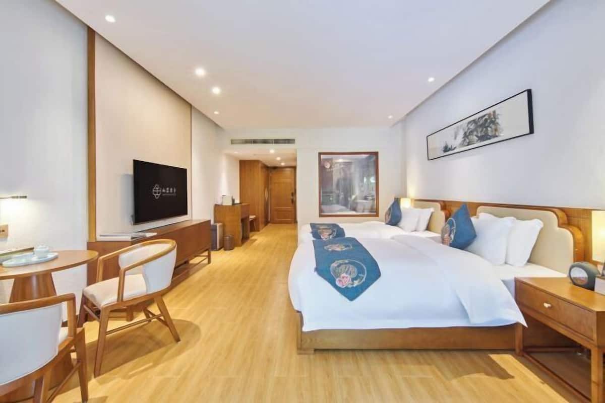 Une chambre d’hôtel comprenant un lit, une table de chevet, une télévision et un bureau avec des chaises.