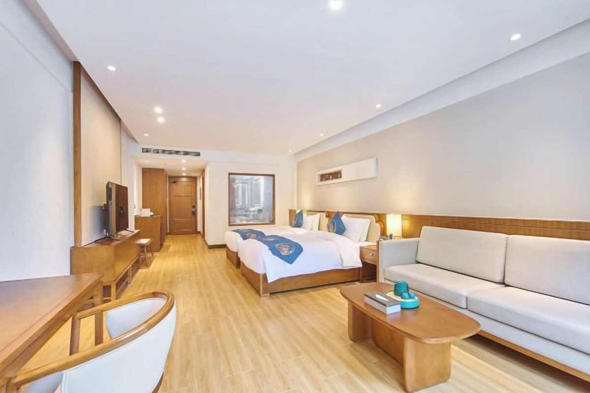 Habitación de hotel con cama, sofá, mesa de centro, escritorio y televisor.