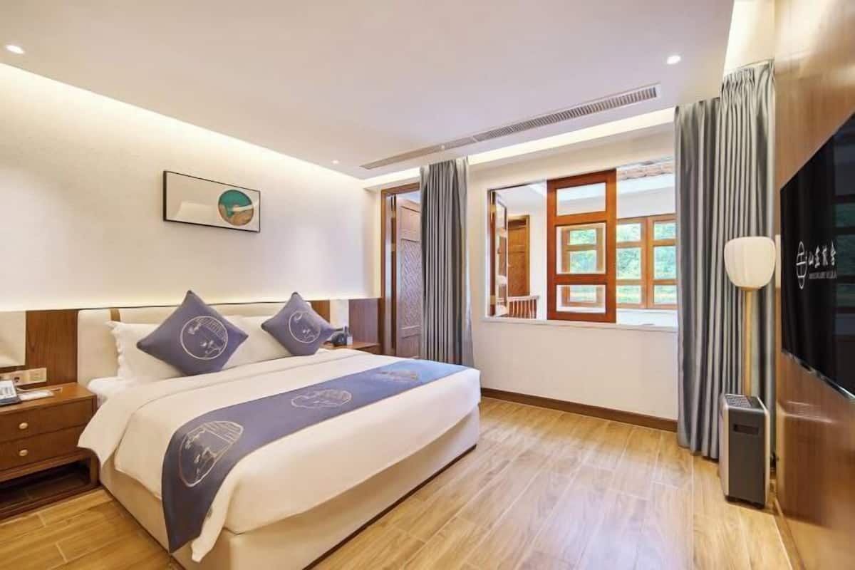 Une chambre d’hôtel avec un lit, une télévision, une fenêtre avec des rideaux et une vue sur l’extérieur.