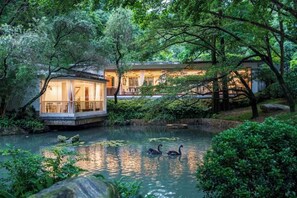 A serene pond with a wooden dock, a small pavilion, and a building with a balcony overlooking the water. - Guangzhou Mountain Villa (Guangzhou)