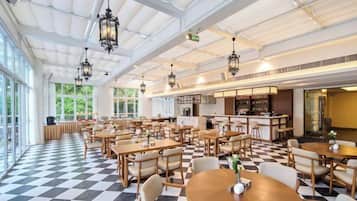 A spacious indoor dining area with high ceilings, large windows, and a checkered floor pattern.