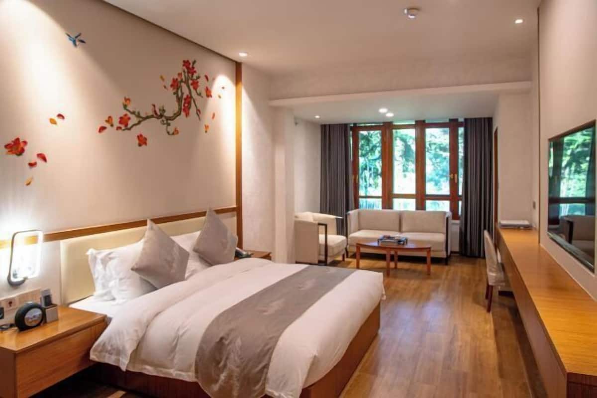 Une chambre d’hôtel avec un grand lit, un canapé, un bureau et une grande fenêtre.