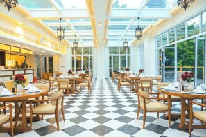 A hotel dining area with checkered flooring, tables with chairs, and large windows. - Guangzhou Mountain Villa (Guangzhou)