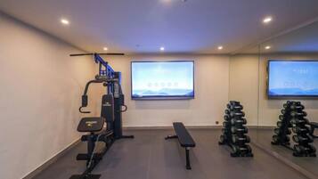 A gym with exercise equipment, a bench, and a television screen.