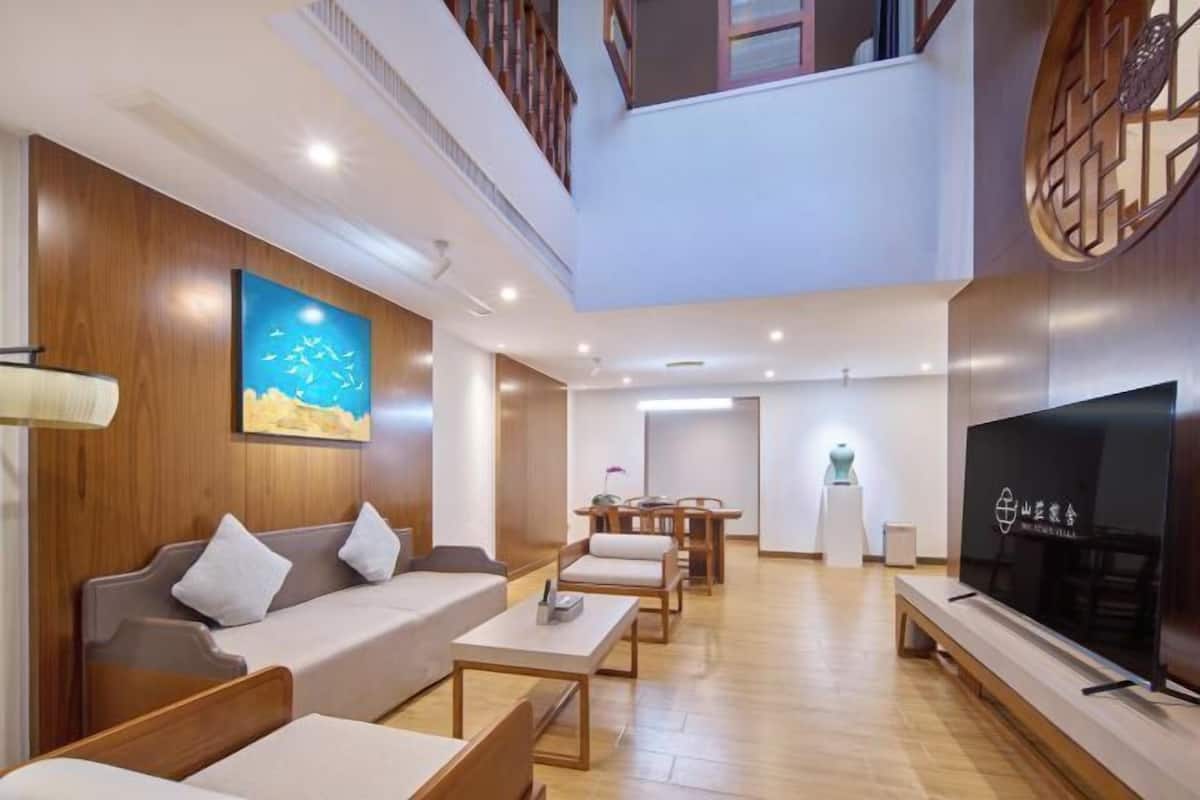 Un salon moderne avec un canapé, une table basse et un téléviseur. Il y a un mur en bois et un tableau accroché au mur.